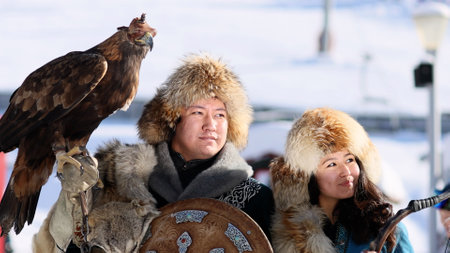Almaty, Kazahstan - 2022. Kazakh Eagle Hunter traditional clothing, while hunting to the hare holding a golden eagle on his arm in mountain of Kazahstan and his wifeのeditorial素材