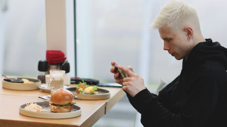 Man Taking Mobile Pictures of Burger with vegetables salad. Social Media Lifestyleの写真素材