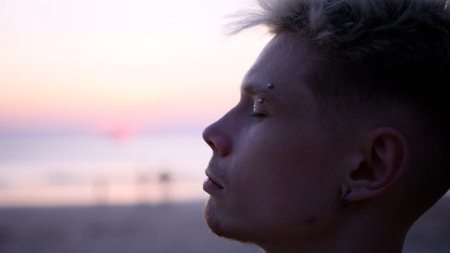 Thoughtful guy looks into the distance on the beach during sunsetの写真素材