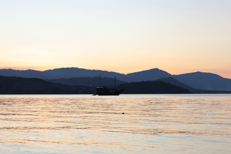 Stunning panoramic view of bay against mountains on horizon with beautiful sunsetの写真素材