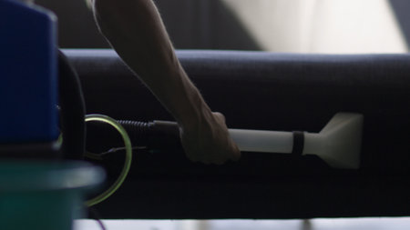 Close up shot of Caucasian person hands using special washing vacuum cleaner equipment washing sofa in room. cleaning furniture.の写真素材