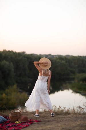 Young pretty woman in dress and hat outdoors posing in a fieldの写真素材