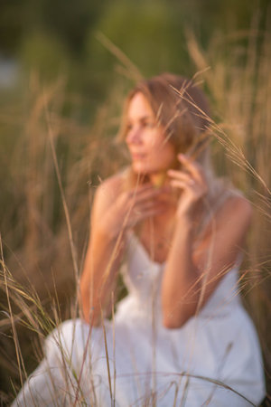 Young pretty woman in dress posing in a fieldの写真素材
