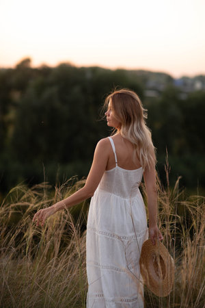 Young pretty woman in dress outdoors posing in a fieldの写真素材