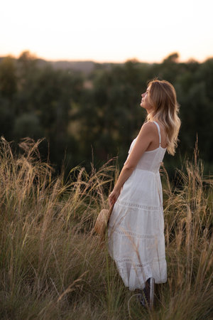 Young pretty woman in dress outdoors posing in a fieldの写真素材