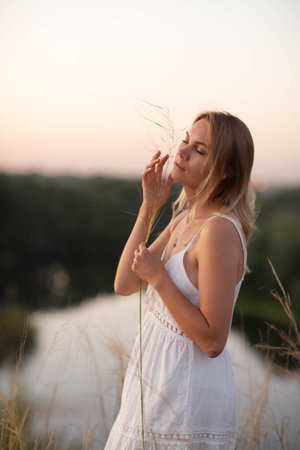 Young pretty woman in dress outdoors posing in a fieldの写真素材