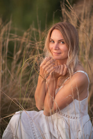 Young pretty woman in dress posing in a fieldの写真素材