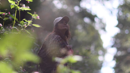 Young Caucasian woman with backpack traveling in the forest. The girl is feeling fresh, wonderful...