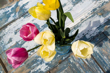 Bouquet of tulips in a vase on a wooden backgroundの写真素材