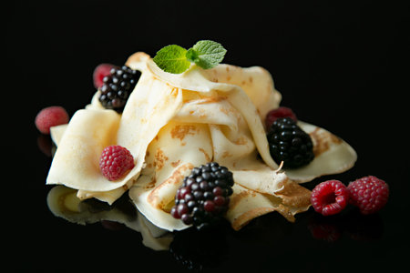 Pancakes with raspberry, blackberry and fresh mint on black glassy background