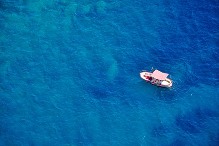 Romantic alone boat in blue sea, bird's eyes view, Capri island, Italyの写真素材