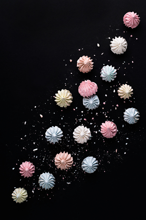 Colorful meringues on dark table. Many sweet zephyrs on black background. Trendy top view sweet dessert image.の写真素材