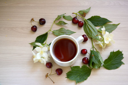 Cup of tea, cherry and flowers on the table. Top viewの写真素材