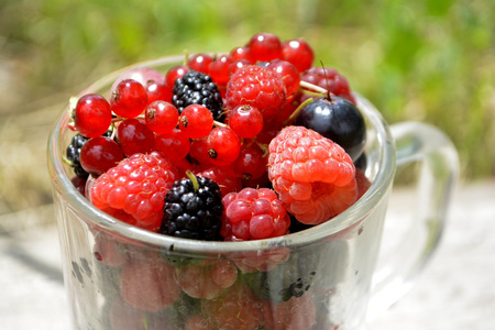 Fresh organic summer berries in a cup. Currant, raspberry, mulberryの写真素材