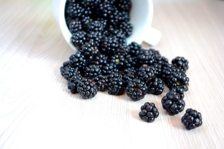 Blackberry falls out of the cup on the table