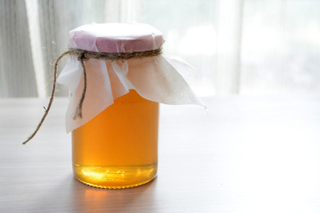 Honey in a transparent jar on the tableの写真素材