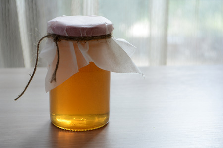 Honey in a transparent jar on the tableの写真素材