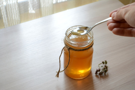 Honey in a transparent jar on the table. Spoon in a jar of honeyの写真素材