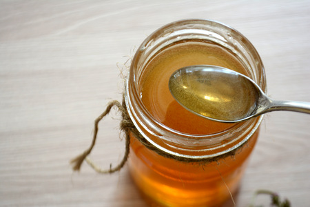 Honey in a transparent jar on the table. Spoon in a jar of honeyの写真素材