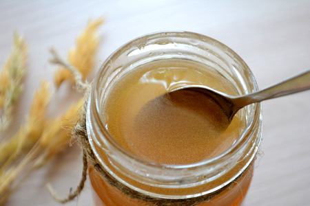 Honey in a transparent jar on the table. Spoon in a jar of honeyの写真素材