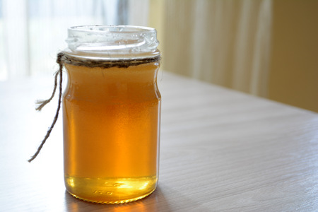 Honey in a transparent jar on the tableの写真素材
