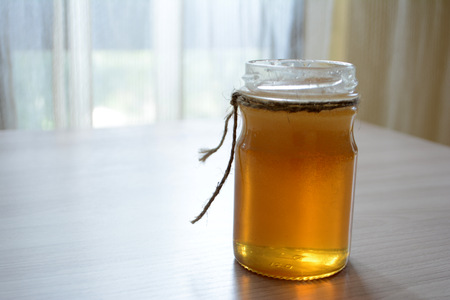Honey in a transparent jar on the tableの写真素材