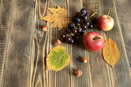 Autumn composition of colorful leaves apple grape and nuts on a wooden background with autumn concept copy spaceの写真素材