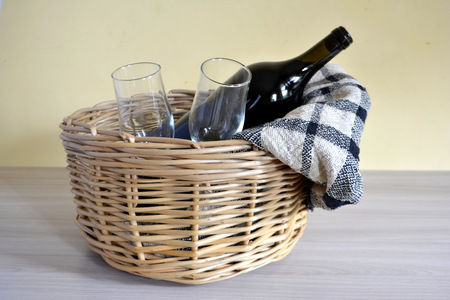 wicker picnic basket with a blanket, bottle of wine, bread and glassesの写真素材