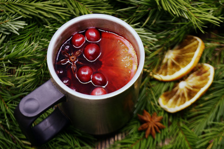 Christmas mulled wine with cranberries in metal mug. Winter warming drink with spices. Decorated with fir branches dried orangesの写真素材