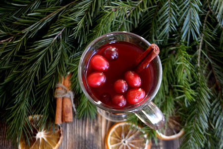 Christmas mulled wine with cranberries in glass. Winter warming drink with spices. Decorated fir branches, cinnamon, dried orangesの写真素材