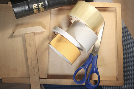 Still life stationery theme. Scissors, tape, ruler lying on wooden surface.の写真素材