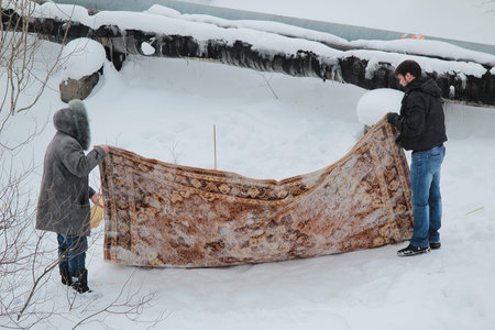 man and woman cleaning the carpet in the snow in winterのeditorial素材