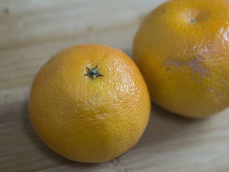 two whole tangerines lie on a wooden surfaceの写真素材