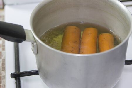 The pan is on the gas stove with carrots insideの写真素材