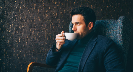 Young man drinking a coffee at the cafeの写真素材