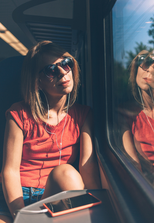 Young woman listening to the music on the trainの写真素材