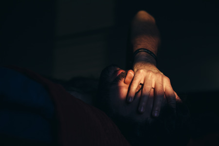 Young man sad and crying in the darkの写真素材