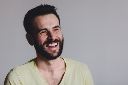 Young bearded man laughing, studio shot.の写真素材