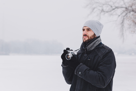 Young man taking a photo on the frozen lake in winter timeの写真素材