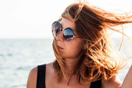 Portrait of a young woman by the sea with wind in her hairの写真素材