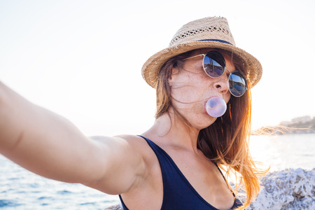 Young woman taking a selfie by the seaの写真素材