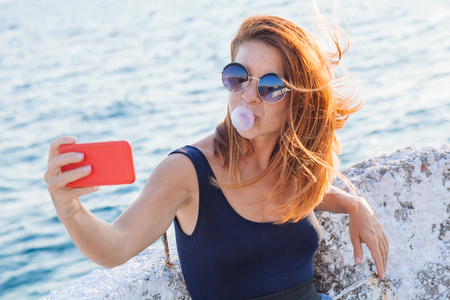 Young woman taking a selfie by the seaの写真素材