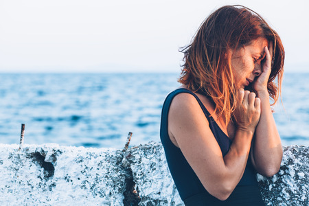 Young woman feeling sad by the seaの写真素材