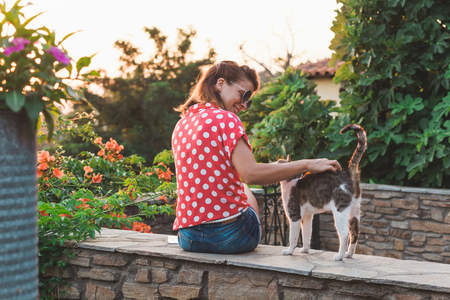 Young woman cuddling a stray cat in the gardenの写真素材