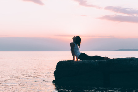 Young woman doing yoga by the seaの写真素材