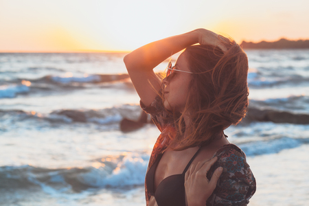 Young woman enjoying sunset and waves at the beachの写真素材