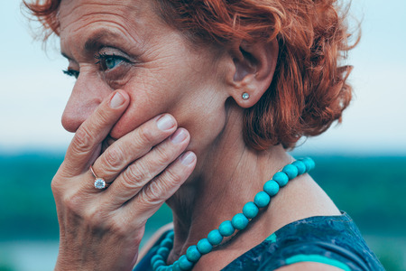 Despressed mature woman feeling lonely outsideの写真素材