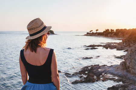 Young woman enjoying sunset on a cliff at a seasideの写真素材