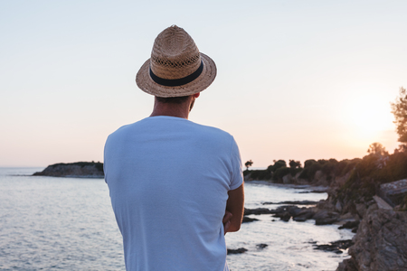 Young man enjoying sunset on a cliff at a seasideの写真素材