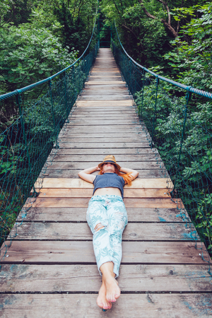 Young woman in the forest lying on the wooden bridge, enjoying summerの写真素材